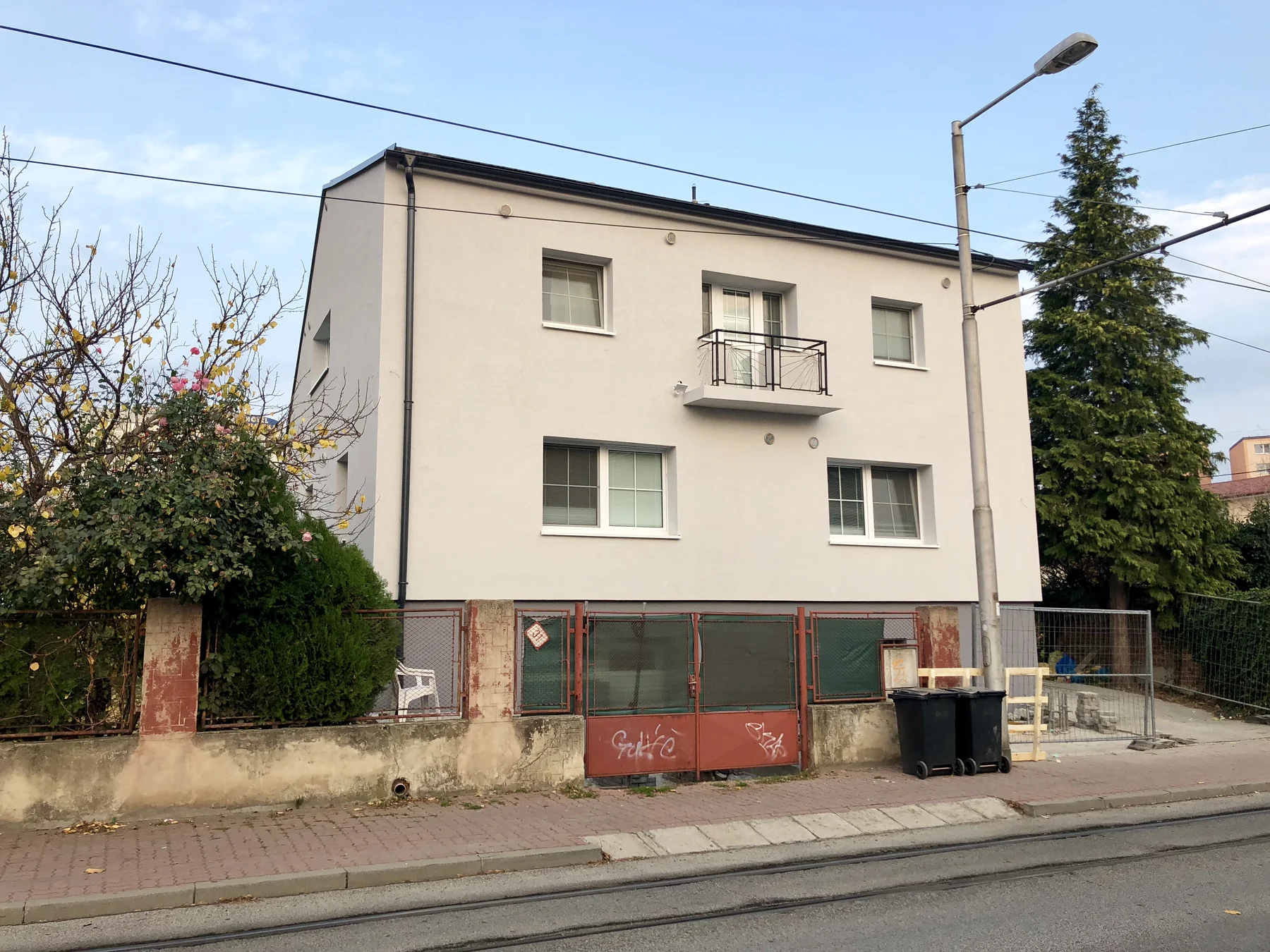 Obnovená svetlá fasáda domu s balkónom a sivým soklom