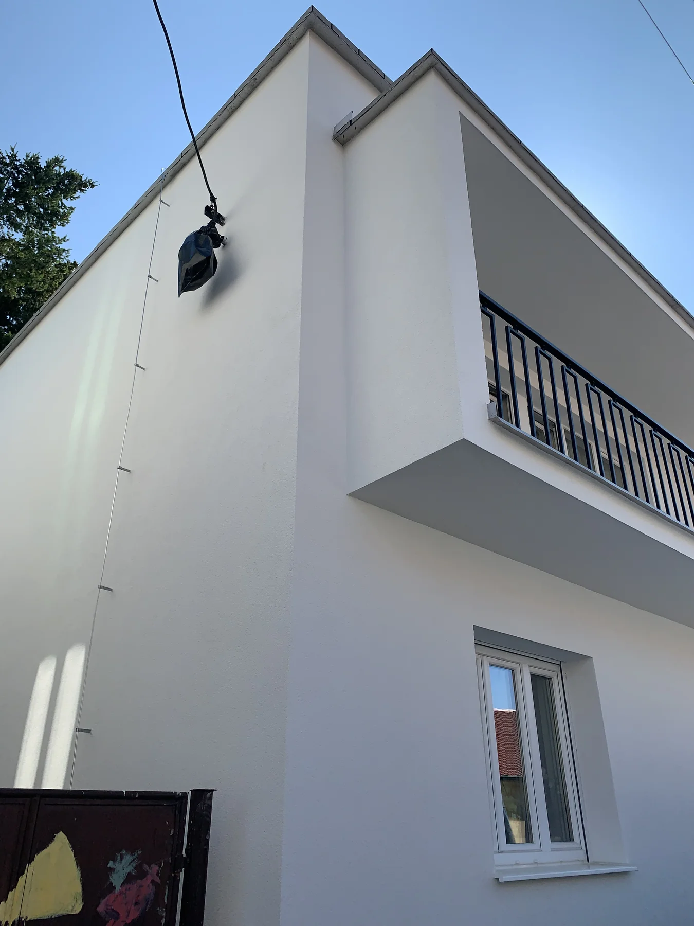 Biela fasáda domu s balkónom pri pohľade z rohu budovy